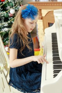 Little girl at a white Grand piano.